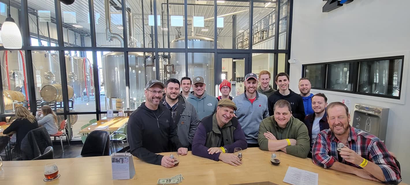 A group posing with pours at the brewery bar