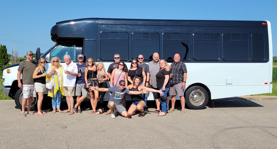 A mixed-age group posing with the bus on a clear day.