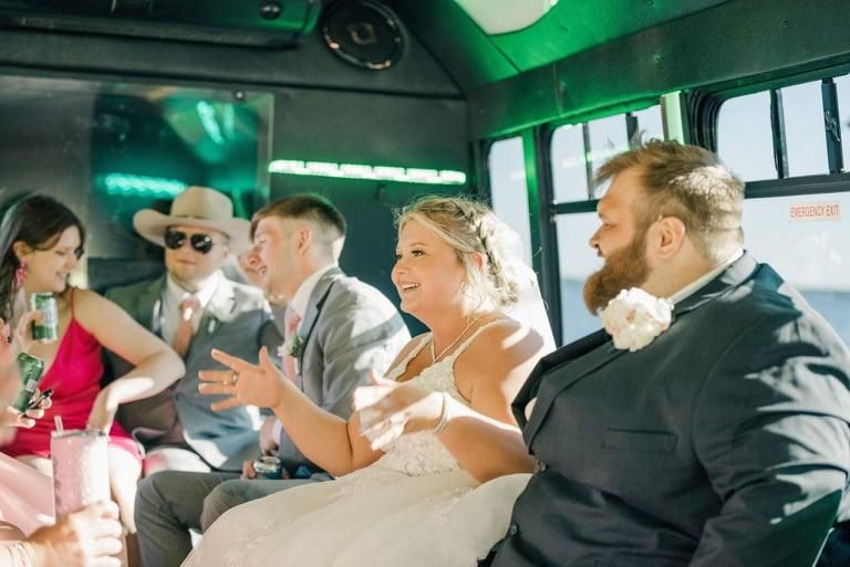 A bride and wedding party laughing on the bus.