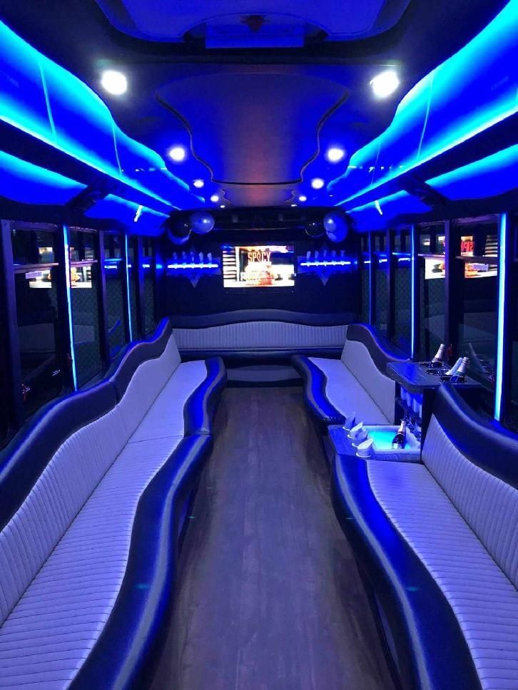 Interior of the Own The Night party bus, lit in blue, with leather benches and a bar.